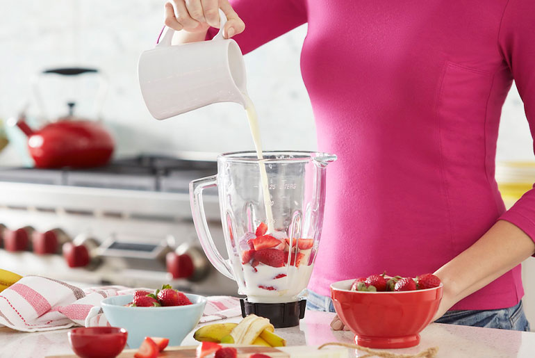 Kvinde tilbereder en proteinshake med Formula 1 og jordbær